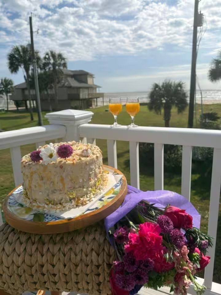 Deck at Beach Therapy with a view toward the Gulf, mimosas, flowers and a cake