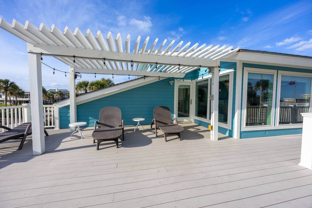 Spacious deck with a pergola, string lights and lounge chairs