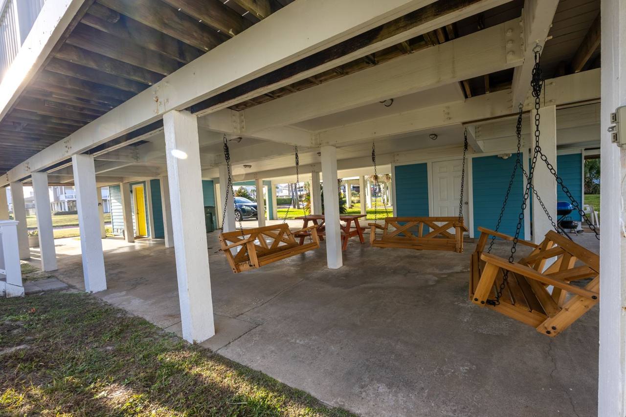 Shaded area under the house with porch swings, a picnic table and a grill