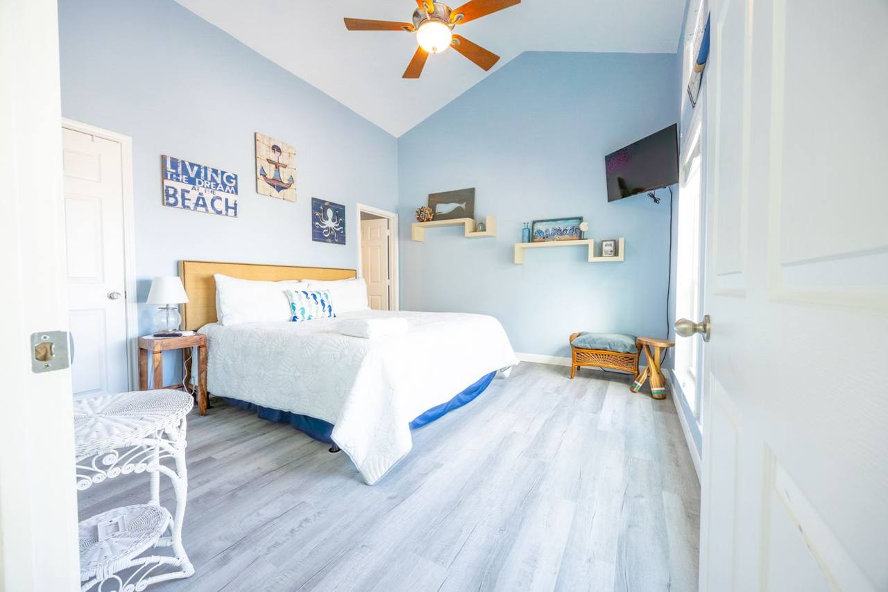 Bedroom with a large bed, wall-mounted TV and ceiling fan