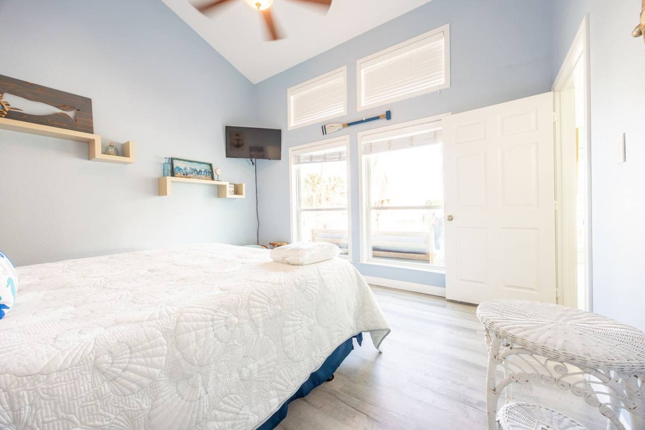 Same bedroom from the window side, with tall windows looking out to the deck