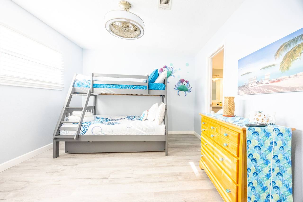 Bunk room with a twin-over-full bunk bed, a trundle underneath, crab wall art and a dresser